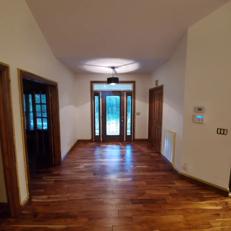 Entry hall with a glass front door and sidelights, hardwood floor, and painted white walls and ceiling