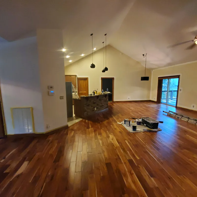 Great room mid-job with paint cans and a drop cloth on the hardwood floor and the kitchen island covered