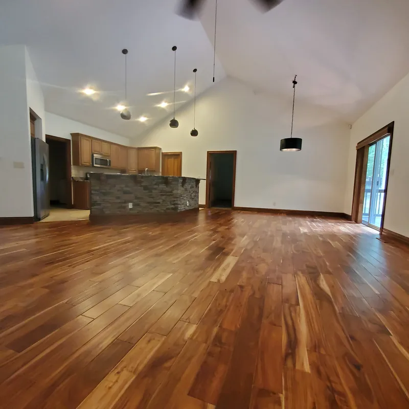 Open-plan great room with a vaulted ceiling, pendant lights, freshly painted white walls and a stone-faced kitchen island